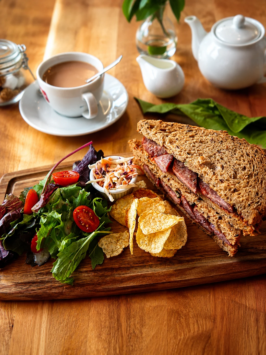 Ham and cheese sandwich with salad, tea and crisps